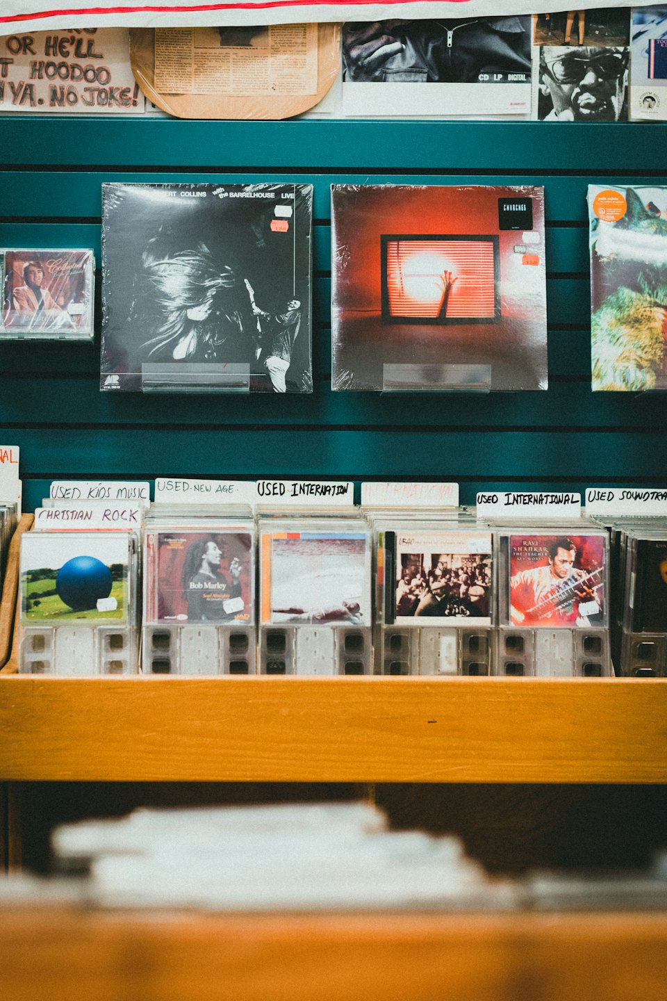 Płyty winylowe i uporządkowane CD wyeksponowane na ścianie sklepu muzycznego.
