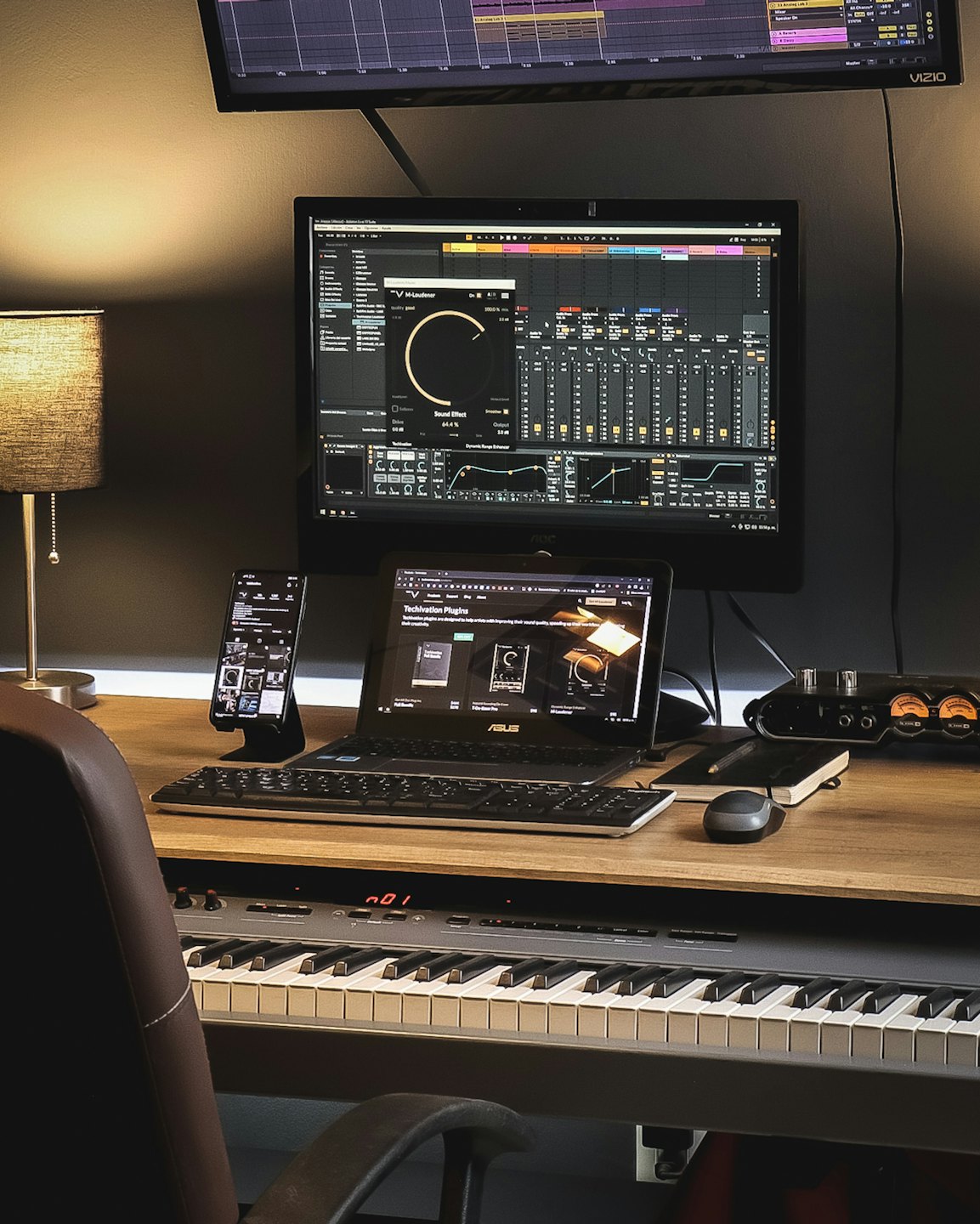 Stanowisko do produkcji muzycznej z wieloma monitorami i klawiaturą.